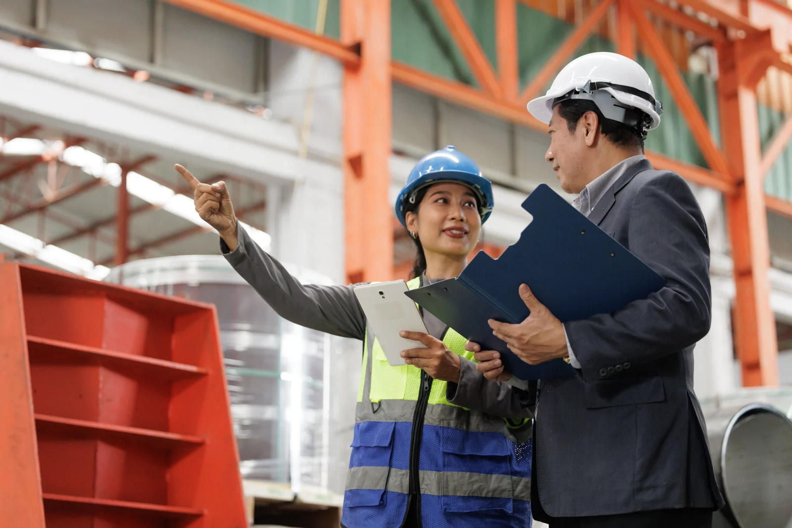 Manajer dan engineer berdiskusi sambil memeriksa area produksi dan penyimpanan di pabrik