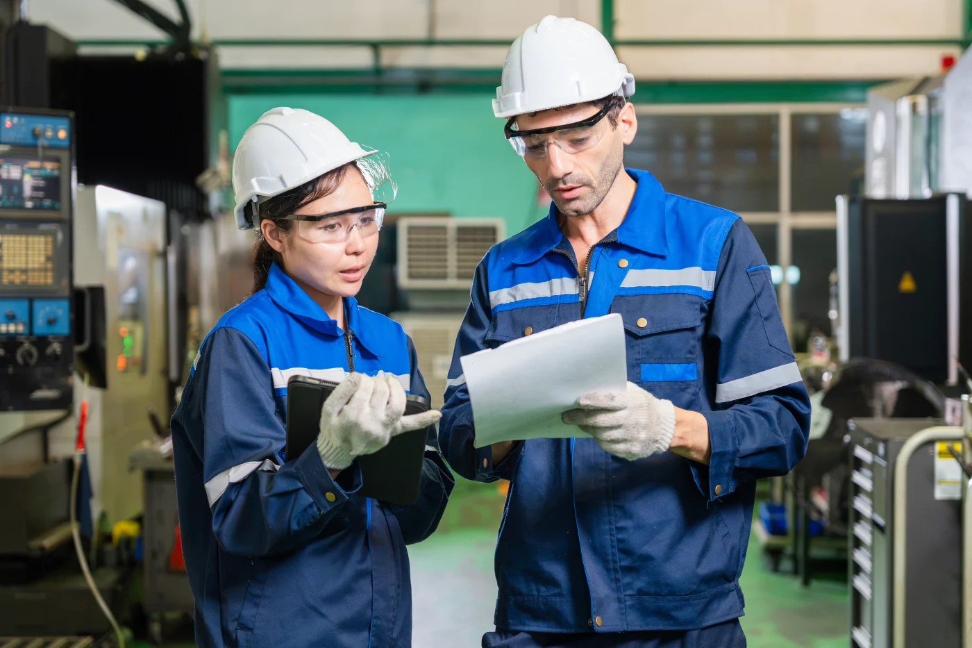 Dua engineer meninjau dokumen dan tablet rencana kendali mutu di pabrik